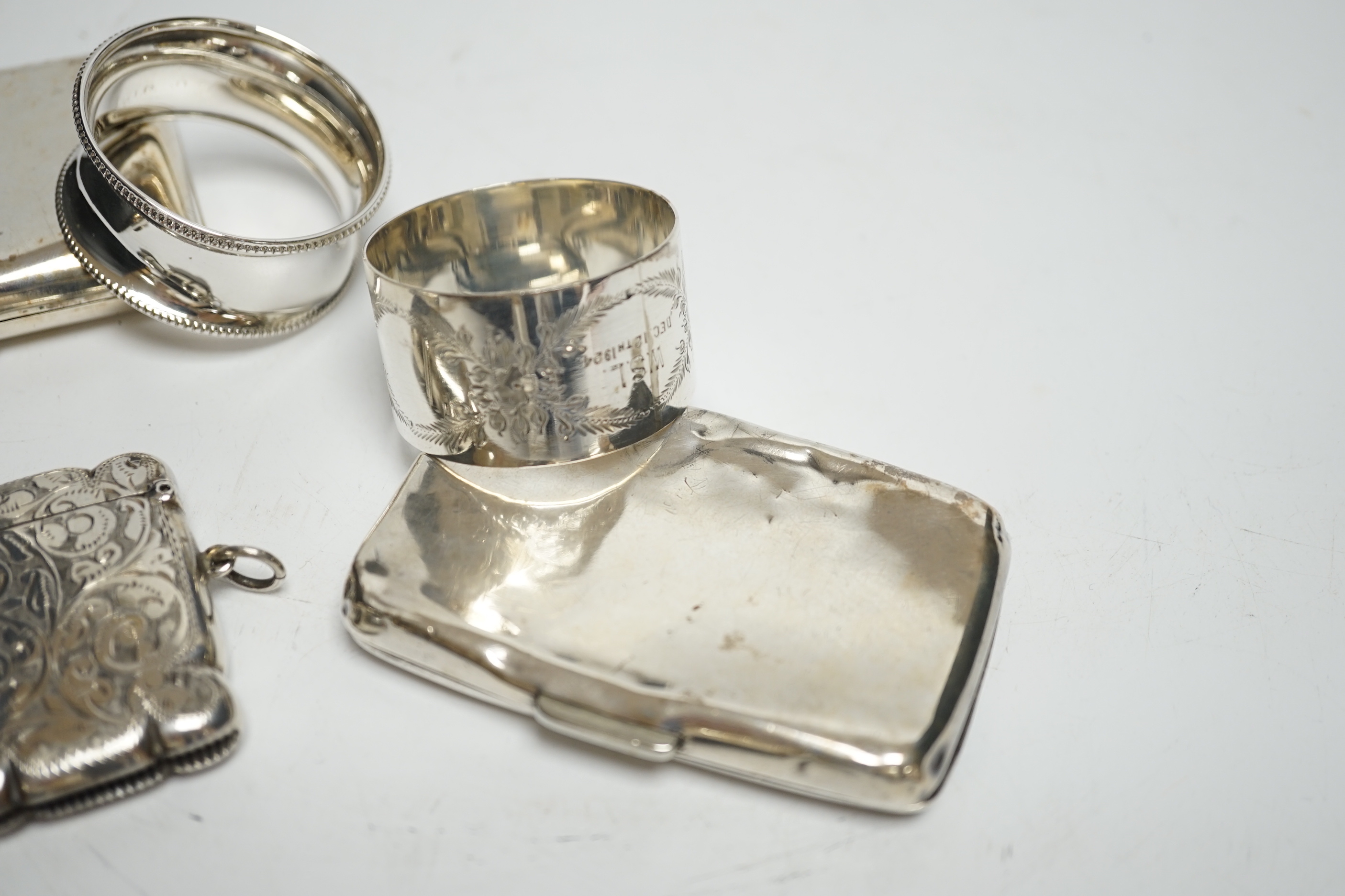 Two silver napkin rings, two silver cigarette cases and two silver vesta cases.